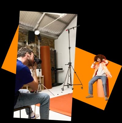Photographer taking a studio portrait of a model posing against an orange backdrop during a professional photoshoot.